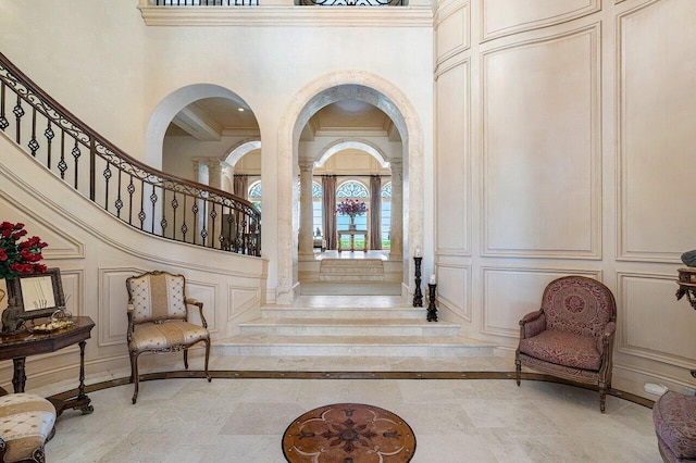 entryway with tile floors, a towering ceiling, and decorative columns