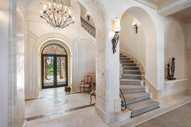 entryway with tile floors, a chandelier, french doors, and crown molding