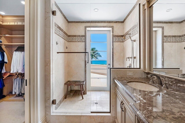 full bathroom featuring ornamental molding, a shower stall, vanity, and a walk in closet