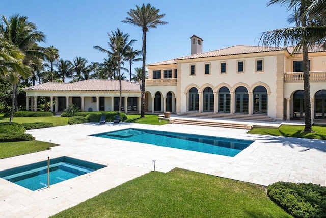 rear view of house with a yard, a chimney, a patio area, a balcony, and an outdoor pool