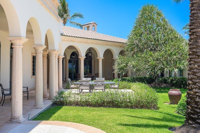 exterior space featuring a tiled roof, a lawn, a patio area, and stucco siding