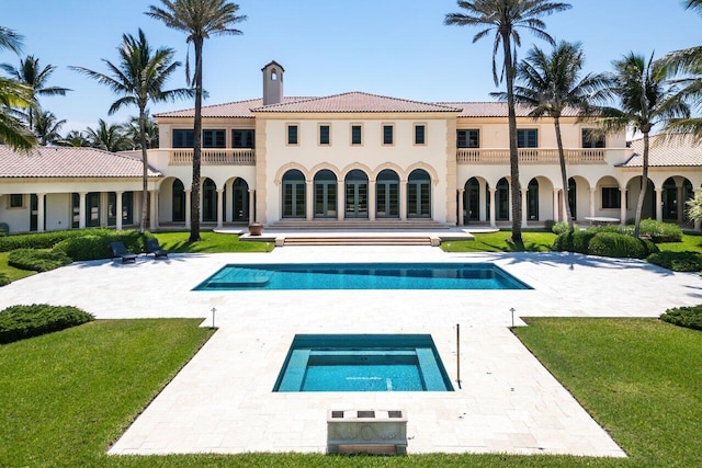 back of house featuring an in ground hot tub, a yard, and a patio area