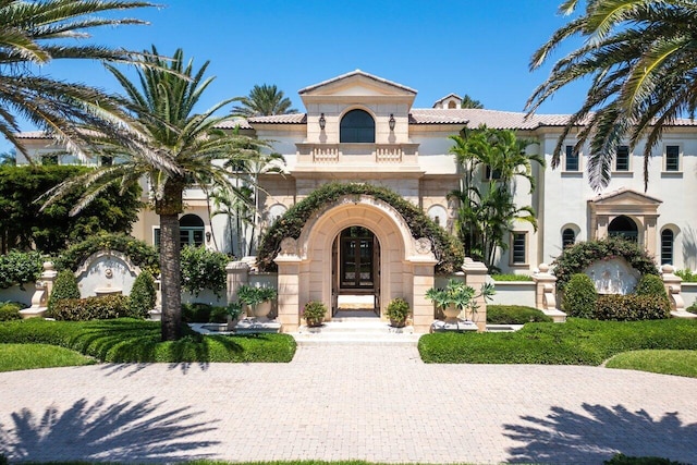 mediterranean / spanish house featuring a tile roof and stucco siding