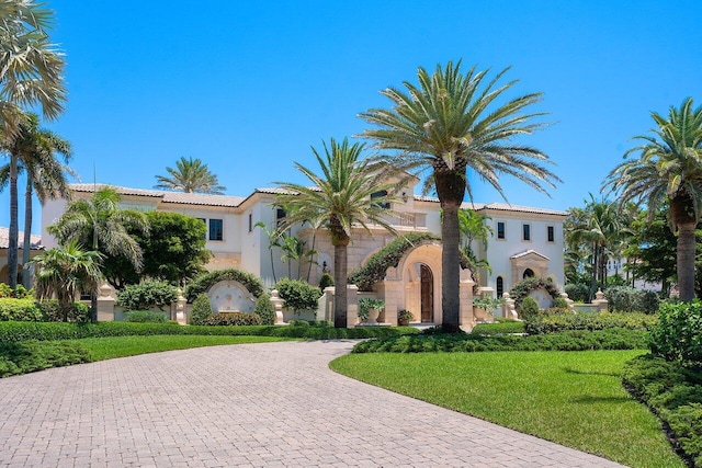 mediterranean / spanish-style home featuring a front yard, decorative driveway, and stucco siding