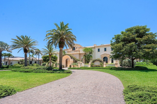 mediterranean / spanish house featuring a front lawn, decorative driveway, and stucco siding