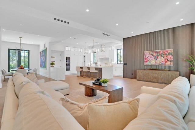 living room featuring a notable chandelier, sink, and light hardwood / wood-style floors