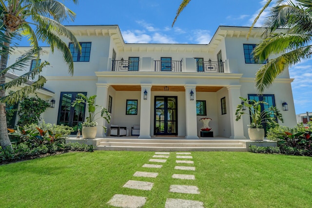 back of property with a yard, french doors, and a balcony