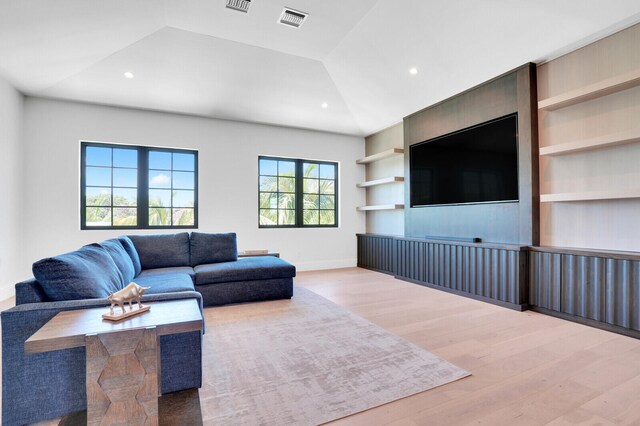 living room with built in features, vaulted ceiling, and wood-type flooring