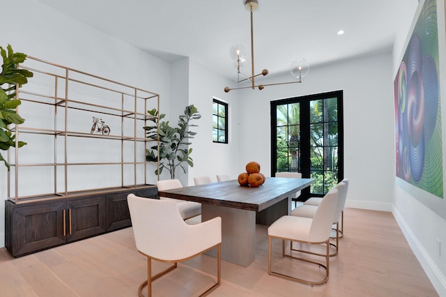 dining area featuring a chandelier, french doors, and light wood-type flooring