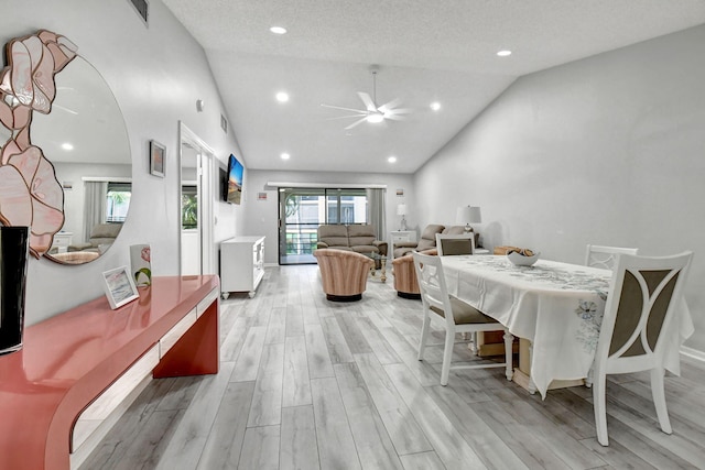 dining space with a textured ceiling, light hardwood / wood-style floors, ceiling fan, and lofted ceiling