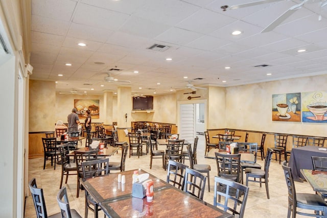 tiled dining space with a drop ceiling and ceiling fan