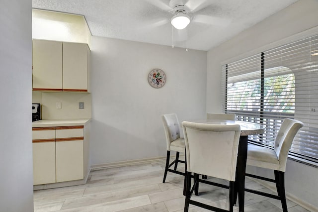 dining room with a textured ceiling, light hardwood / wood-style floors, and ceiling fan