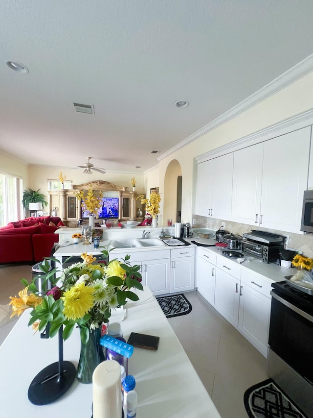 kitchen with white cabinets, crown molding, ceiling fan, electric range oven, and kitchen peninsula