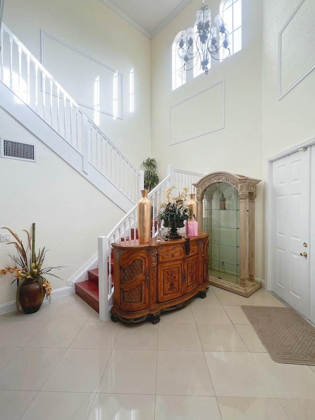 tiled foyer with a towering ceiling, ornamental molding, and an inviting chandelier