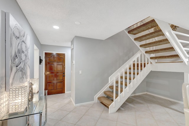 staircase with a textured ceiling and tile patterned floors