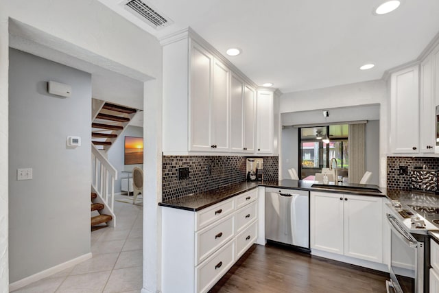 kitchen with white cabinetry, dark stone countertops, decorative backsplash, light tile patterned floors, and appliances with stainless steel finishes