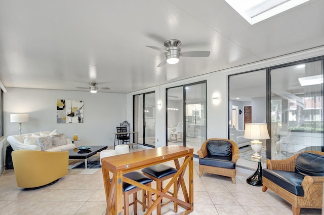 tiled dining room featuring a skylight, ceiling fan, and a healthy amount of sunlight