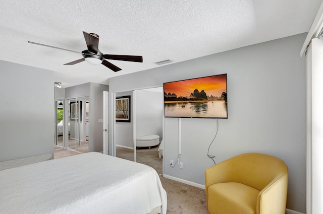 bedroom with a textured ceiling, light colored carpet, and ceiling fan