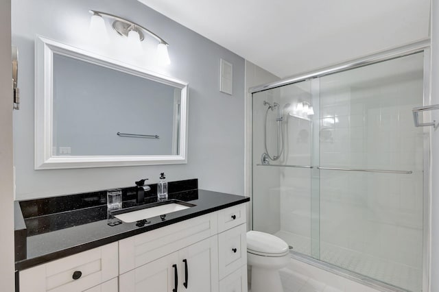 bathroom with tile patterned floors, vanity, toilet, and an enclosed shower