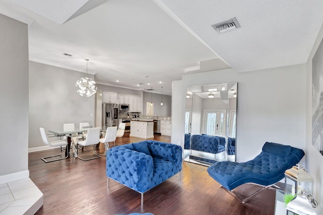 living room with crown molding, dark hardwood / wood-style floors, and an inviting chandelier