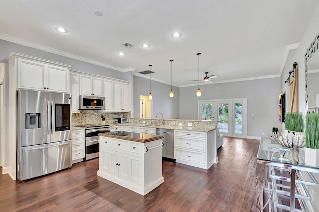 kitchen featuring kitchen peninsula, appliances with stainless steel finishes, decorative light fixtures, and white cabinetry