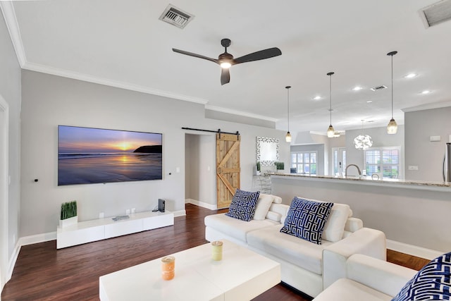 living room featuring a barn door, ceiling fan, dark wood-type flooring, and ornamental molding