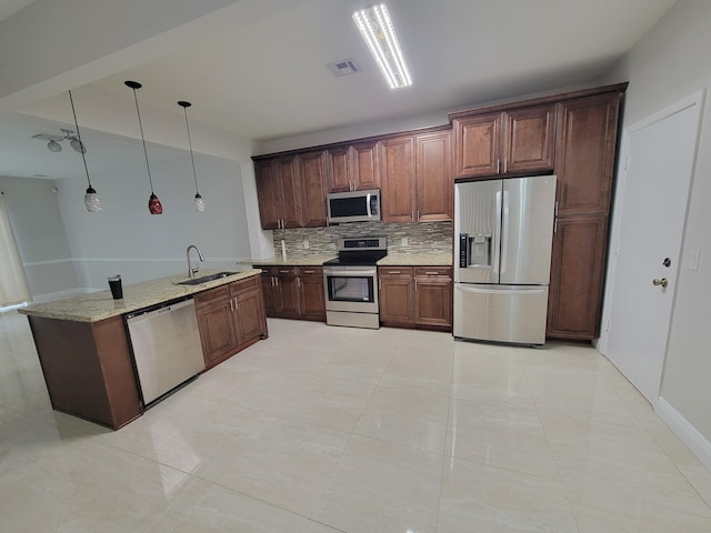 kitchen featuring sink, decorative backsplash, light tile patterned floors, appliances with stainless steel finishes, and decorative light fixtures