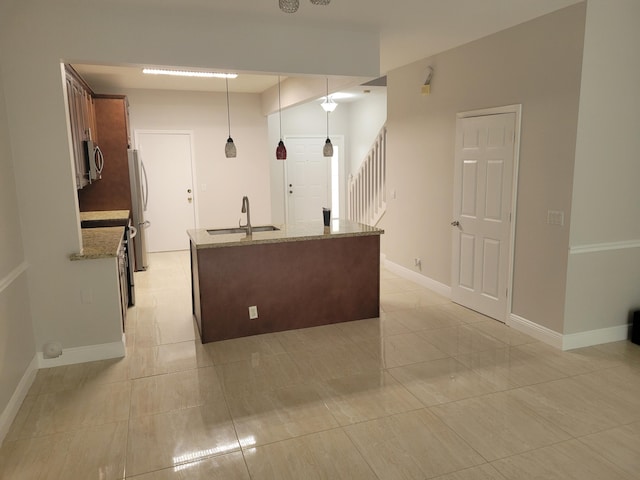 kitchen featuring appliances with stainless steel finishes, light stone counters, hanging light fixtures, and sink