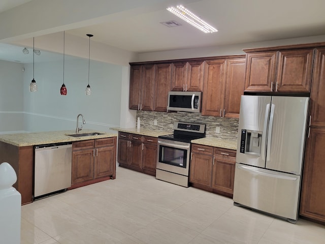 kitchen featuring sink, light stone counters, backsplash, decorative light fixtures, and appliances with stainless steel finishes