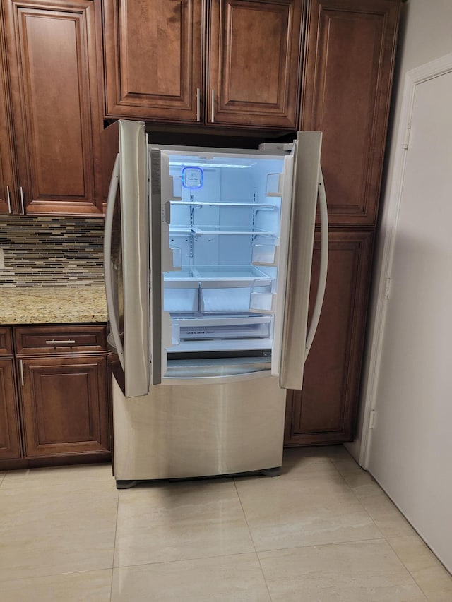 interior space with light stone counters, stainless steel refrigerator, and tasteful backsplash