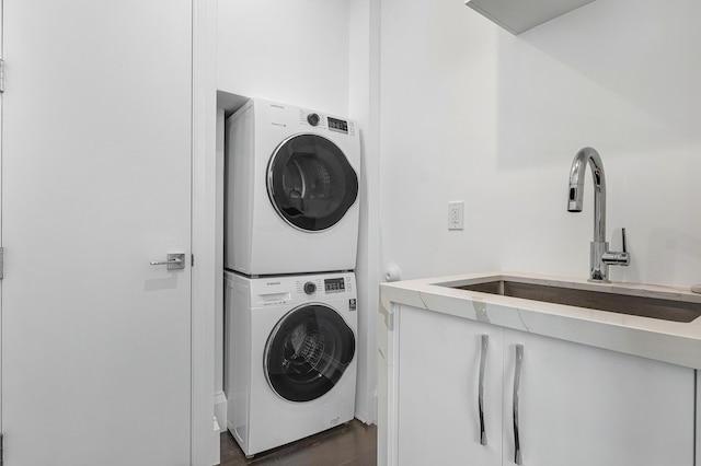 laundry room featuring stacked washing maching and dryer, sink, and dark wood-type flooring