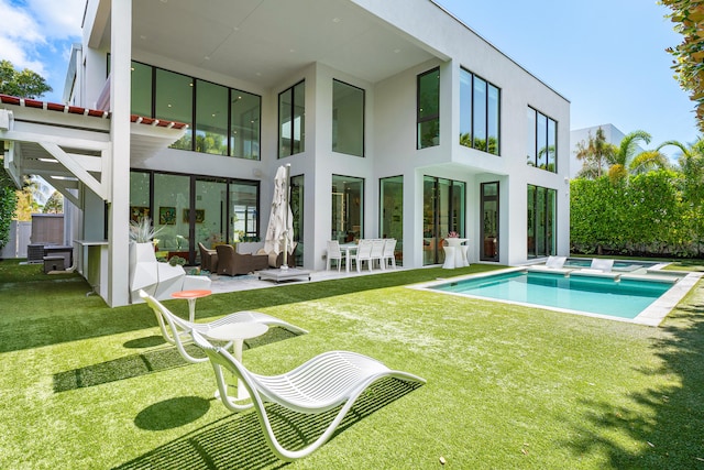 rear view of house featuring a patio area, a yard, an outdoor living space, and a fenced in pool