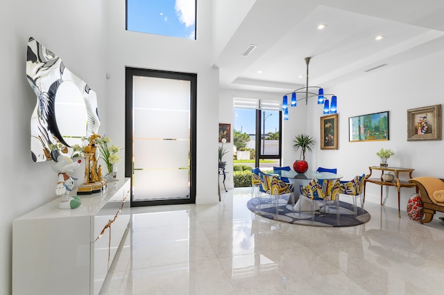 tiled foyer featuring a high ceiling and a raised ceiling