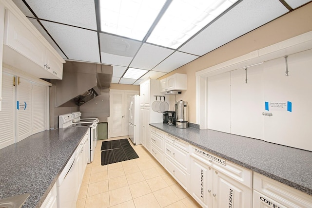 kitchen with a paneled ceiling, white cabinets, white appliances, and light tile patterned floors