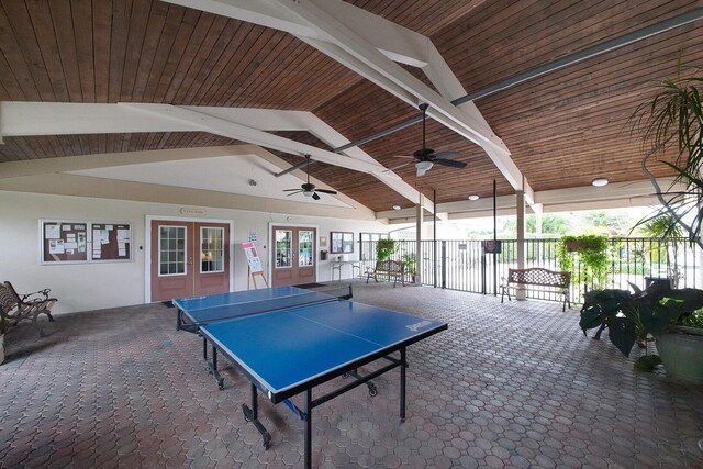 recreation room with ceiling fan, wooden ceiling, beam ceiling, dark carpet, and french doors