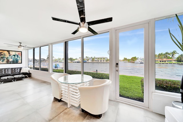 sunroom with ceiling fan, a healthy amount of sunlight, and a water view