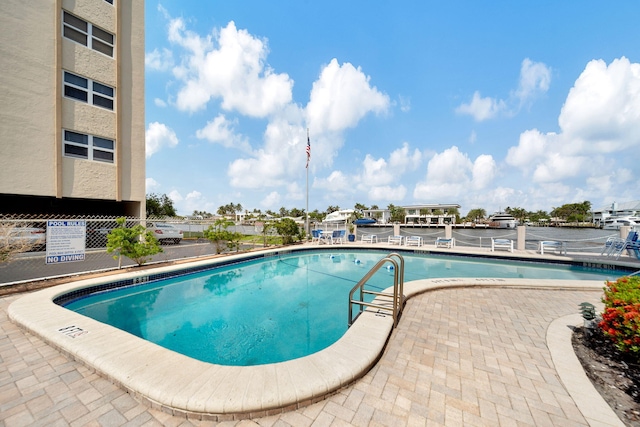 view of pool with a water view and a patio area