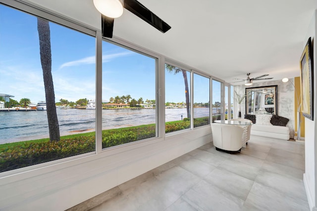 sunroom / solarium featuring ceiling fan and a water view