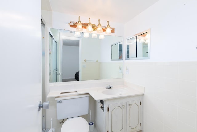 bathroom with vanity, toilet, and tile walls