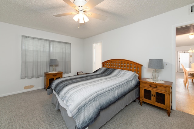 bedroom featuring ceiling fan, light colored carpet, and a textured ceiling