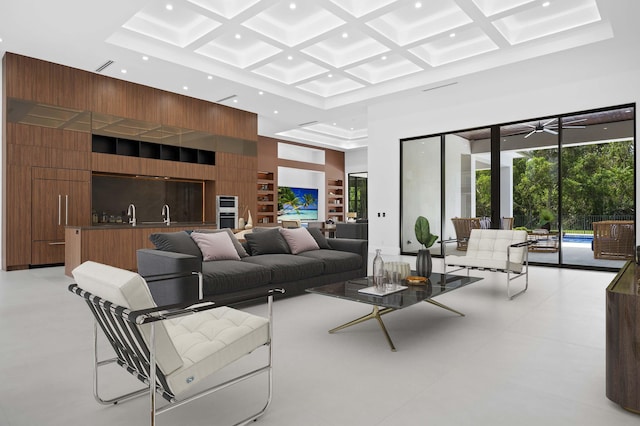 living room with a high ceiling, ceiling fan, and coffered ceiling