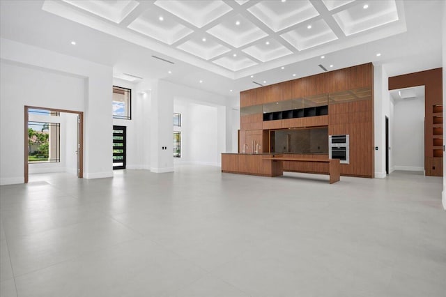 unfurnished living room with a towering ceiling, beam ceiling, and coffered ceiling