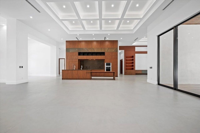 unfurnished living room with coffered ceiling, a high ceiling, and beam ceiling