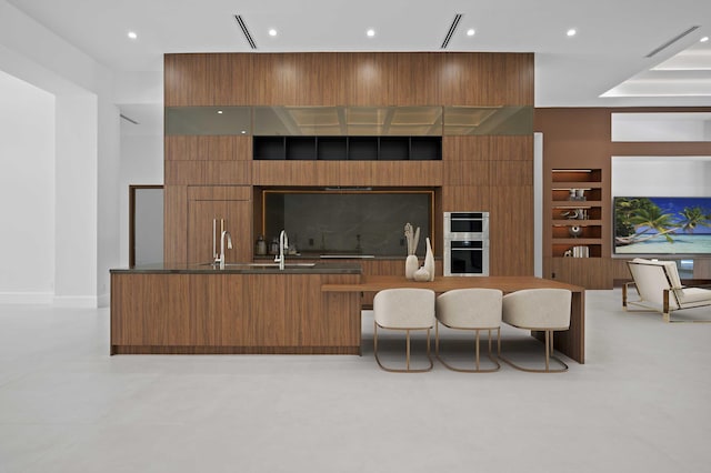 kitchen featuring double oven, sink, and built in shelves