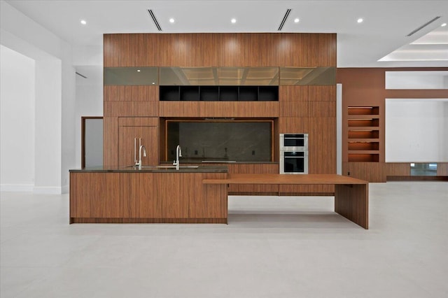 kitchen featuring double oven, built in shelves, and sink