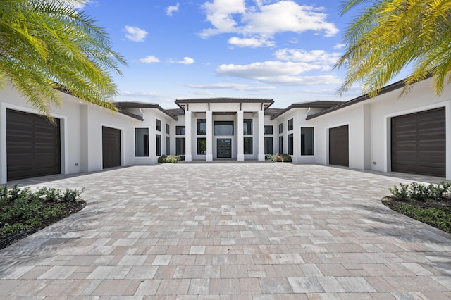 view of front facade with a garage, decorative driveway, and stucco siding