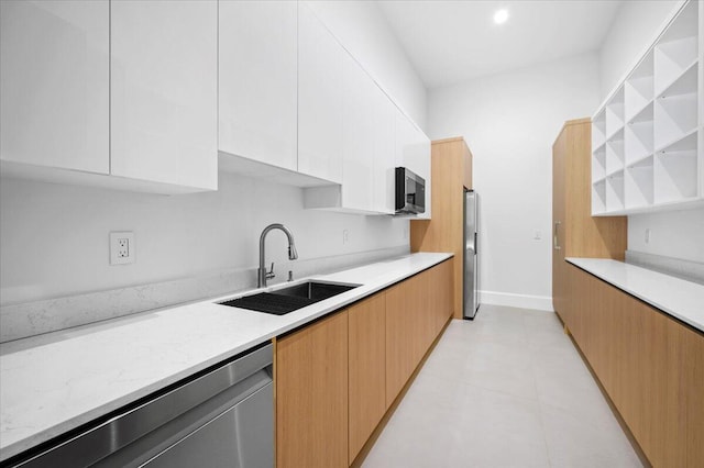 kitchen featuring sink, stainless steel appliances, light stone counters, and white cabinetry