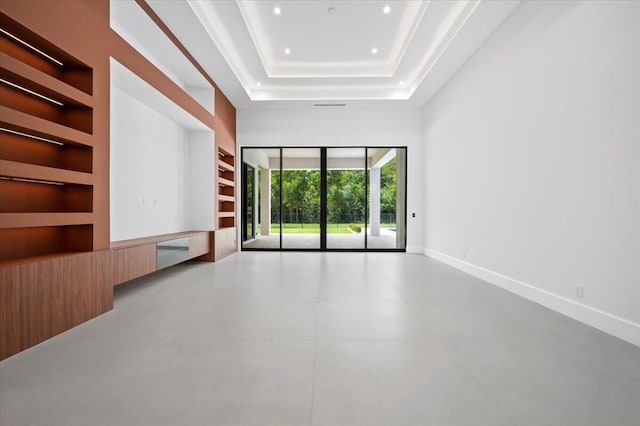 unfurnished living room with a raised ceiling and built in shelves