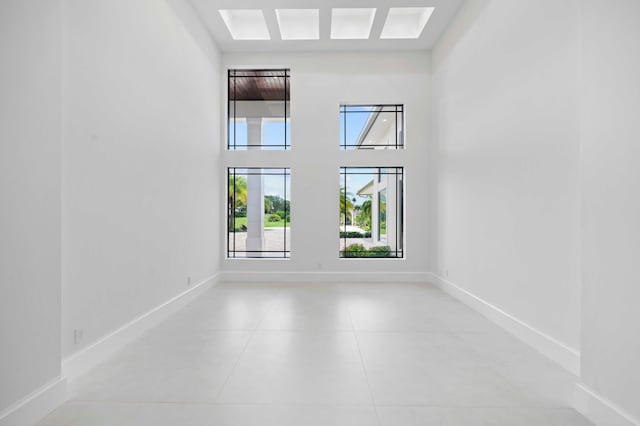 tiled empty room featuring a towering ceiling