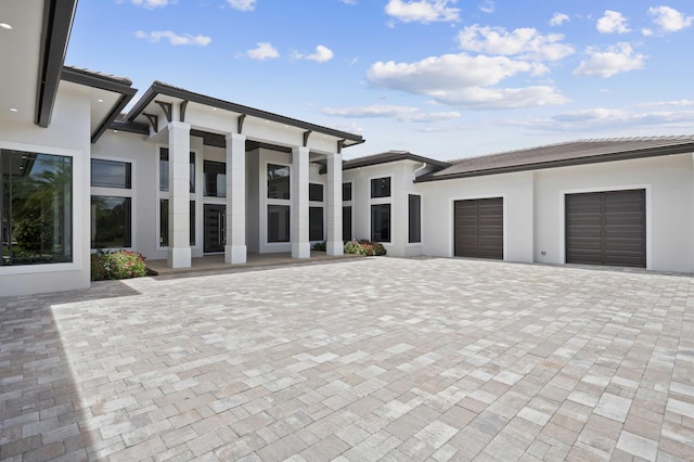 exterior space featuring a garage, decorative driveway, and stucco siding